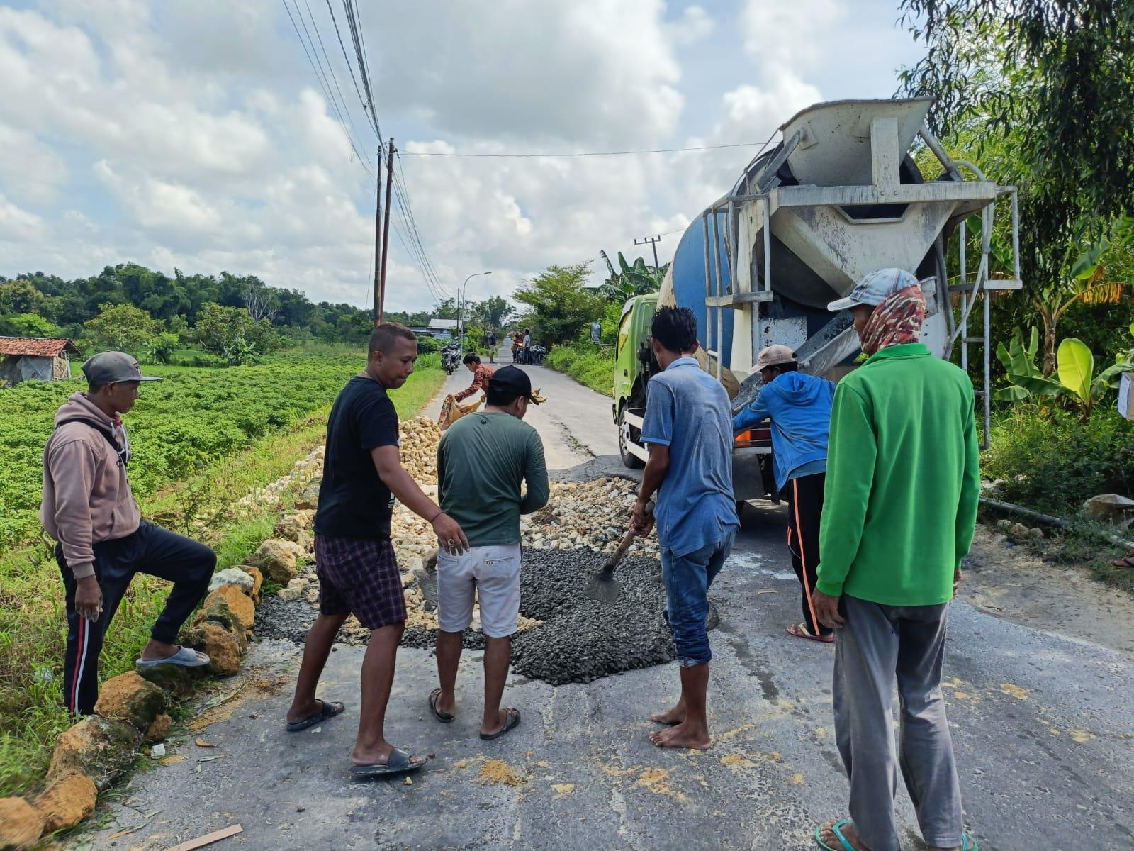 Warga tengah memperbaiki poros jalan kabupaten yang terletak di Desa Bandaran, Tlanakan, Pamekasan.