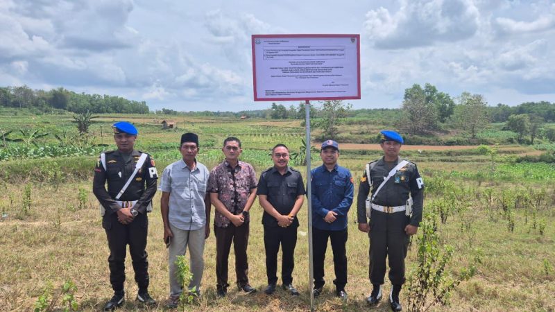 Keterangan foto: Kejari Pamekasan saat memasang plang penyitaan aset di tanah milik H, Agen UPS Palengaan, Pamekasan.