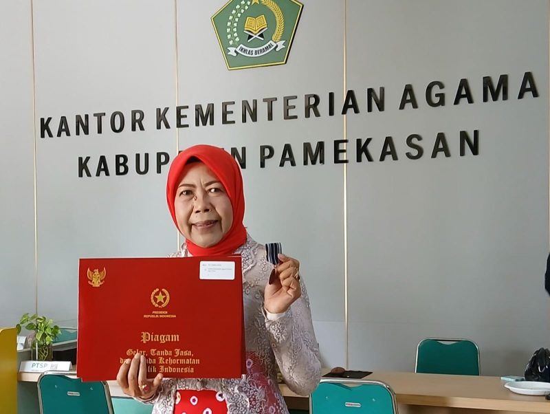 Guru MAN 2 Pamekasan, Chandra Kirana memperlihatkan Satyalancana Karya Satya dari Presiden Prabowo.