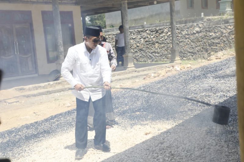 Bupati Pamekasan, KH Kholilurrahman saat bekerja bakti pengaspalan jalan bersama warga.