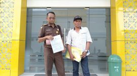 Keterangan foto: Mohammad Andra Setyabudi, SH (40), seorang Pegawai Negeri Sipil asal Bangkalan, didampingi saudaranya menunjukkan LP di depan SPKT Polres Pamekasan.