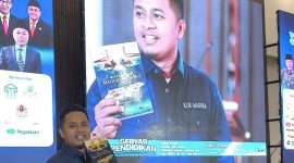 Prengki Wirananda tengah menunjukkan buku yang baru saja diluncurkan.