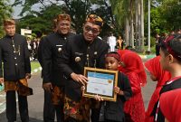 Bupati Pamekasan, KH Kholilurrahman saat memberikan piagam penghargaan kepada siswa berprestasi.