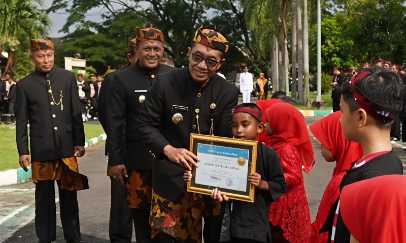 Bupati Pamekasan, KH Kholilurrahman saat memberikan piagam penghargaan kepada siswa berprestasi.